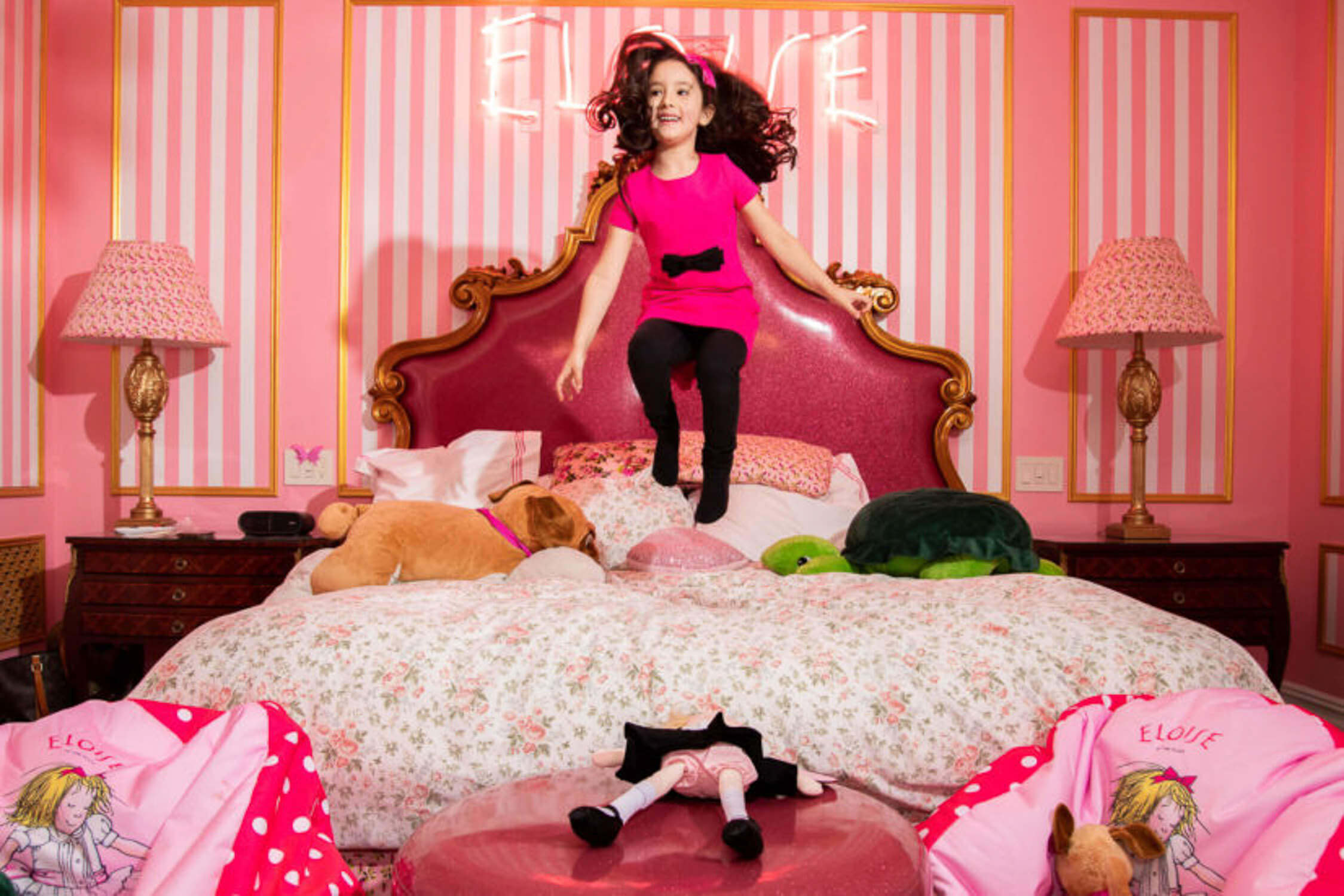 Girl holding a yellow balloon dog and purple heart balloons, standing stylishly on a city street.