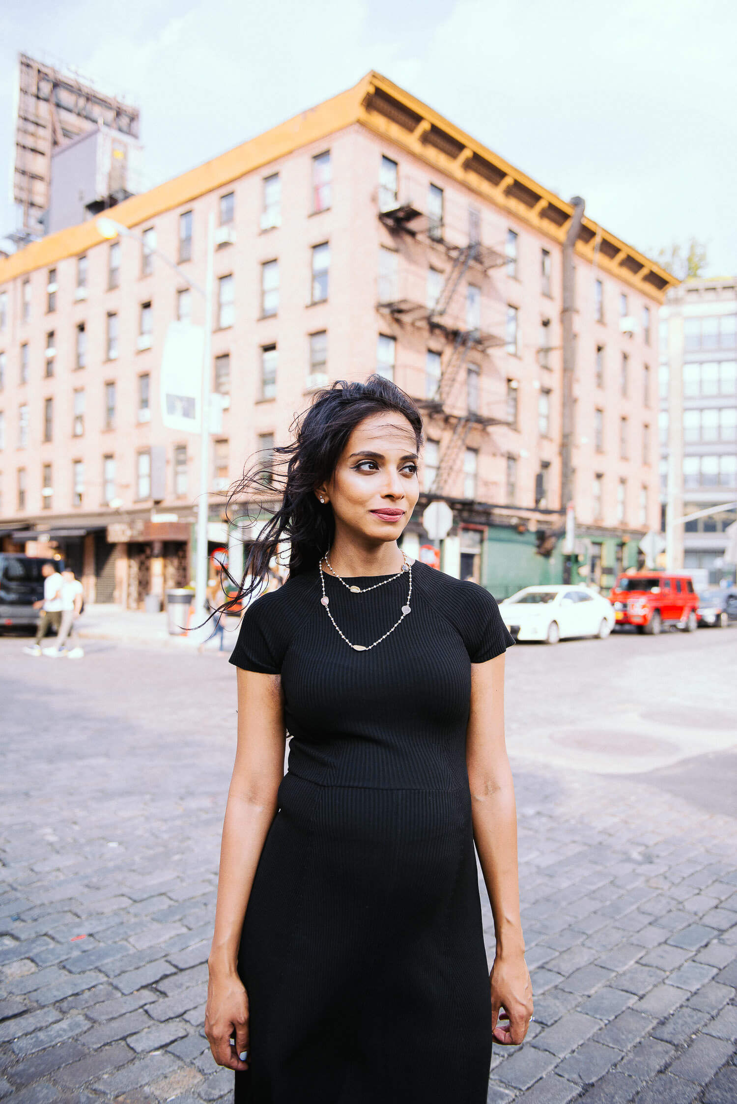 Expectant couple standing together, holding hands, with a concrete wall backdrop