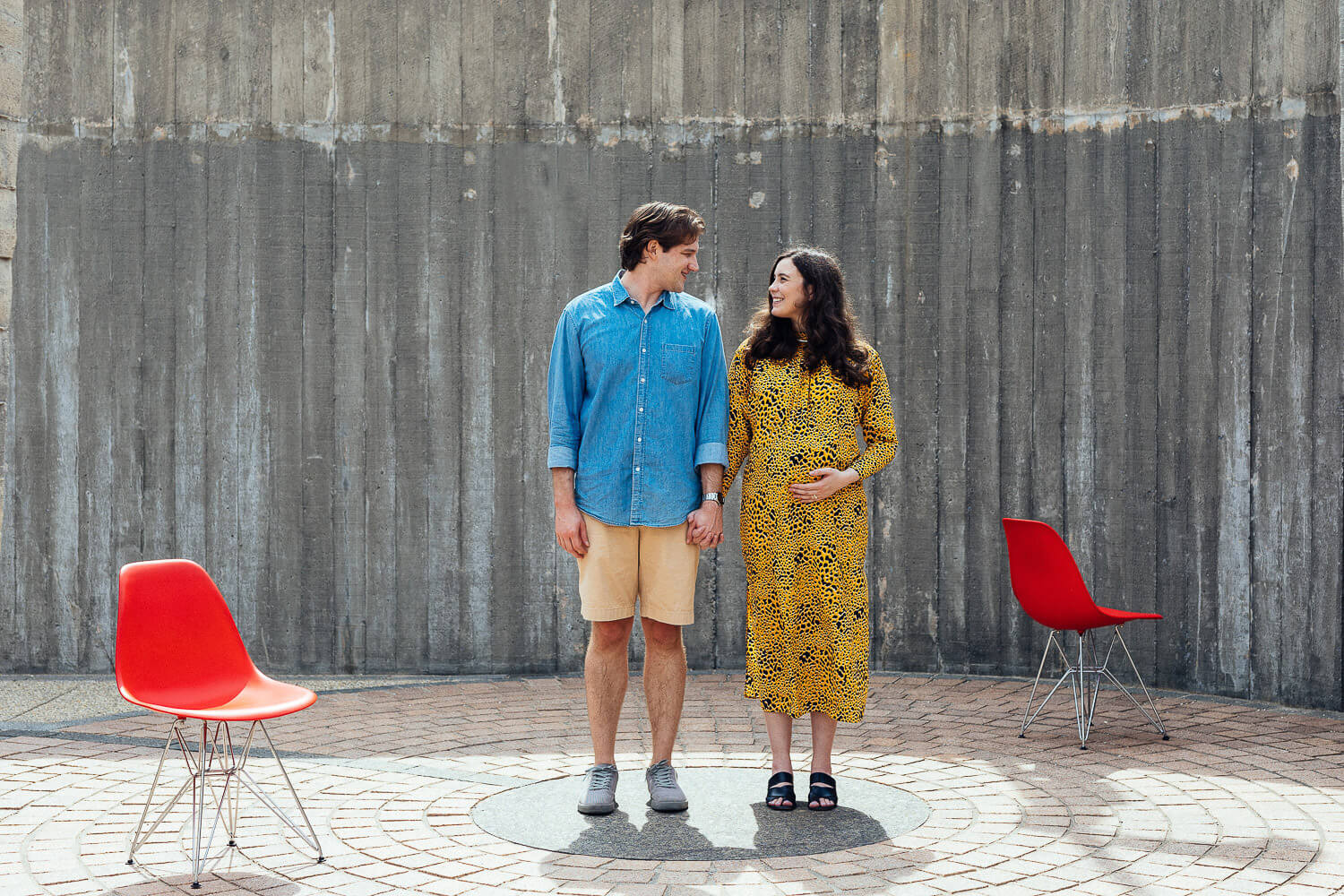 Expectant couple standing together against a modern, industrial wall
