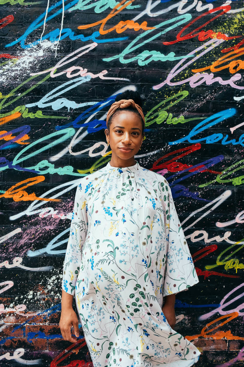 Pregnant woman standing in front of a vibrant graffiti wall in NYC